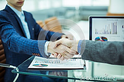 Handshake financial partners on the background of the workplace with financial papers Stock Photo