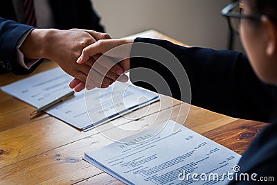 Handshake success job interviewing. Job applicant having interview. Shaking Hand With Resume On Desk. Employer giving an handshake Stock Photo