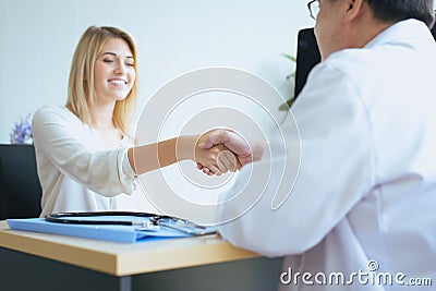 Handshake woman patient and man doctor reassuring consultation and encouragement in hospital room,Close up Stock Photo