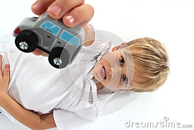 Handsome adorable fair hair boy showing a wooden car toy and making a special facial attitude Stock Photo