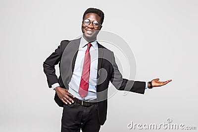 Handsome African American man in a black business suit gesturing as if to demonstrate a product sample on grey Stock Photo