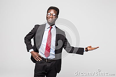 Handsome African American man in a black business suit gesturing as if to demonstrate a product sample on grey Stock Photo