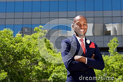 Handsome african businessman smiling by building in city Stock Photo