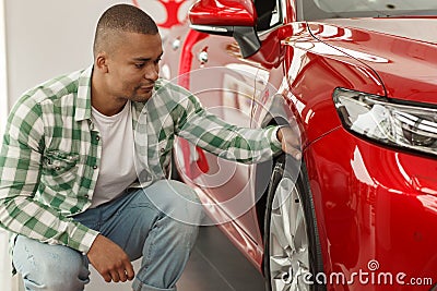 Handsome African man choosing new car at dealership Stock Photo