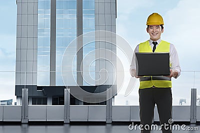 Handsome asian architect man with laptop wearing protective helm Stock Photo