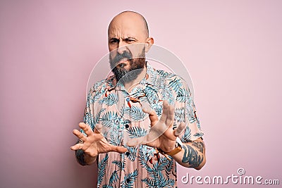 Handsome bald man with beard and tattoo wearing casual floral shirt over pink background disgusted expression, displeased and Stock Photo