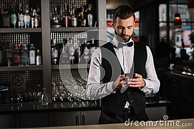 handsome bartender using smartphone Stock Photo