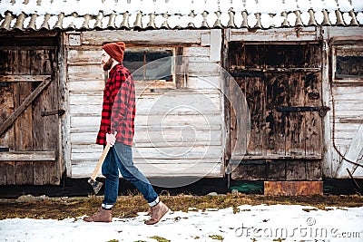 Handsome bearded man holding axe and walking in village Stock Photo