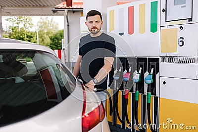 Handsome bearded man refueling car at self service gas station. Petrol concept Stock Photo