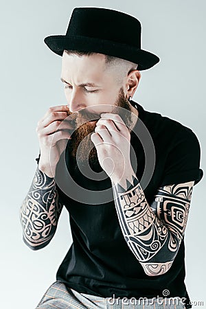 handsome bearded tattooed man twisting mustache Stock Photo