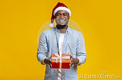 Handsome black guy in red Santa hat holding gift box Stock Photo