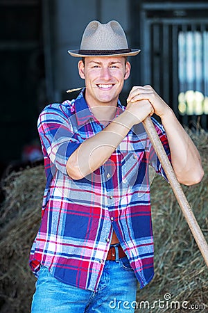 Blond man at a barn holdiing pitchfork Stock Photo