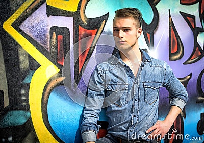 Handsome blond young man against colorful graffiti wall Editorial Stock Photo