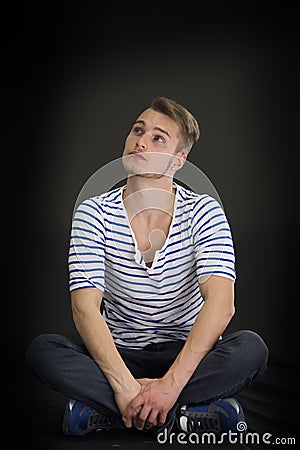 Handsome blond young man sitting on black background Stock Photo