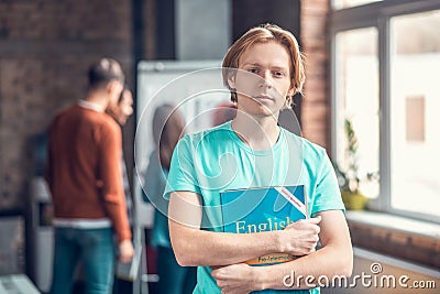 Handsome blue-eyed student holding English grammar book Stock Photo