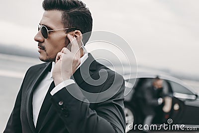 handsome bodyguard of businessman listening message Stock Photo