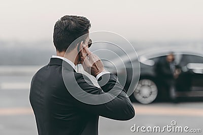 handsome bodyguard standing and listening message with security earpiece Stock Photo