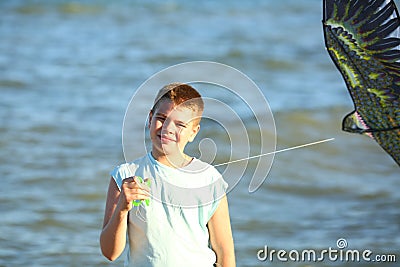 Handsome boy in shorts and a t-shirt teenager launches a kite on the sky on the seashore Stock Photo