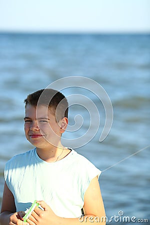 Handsome boy in shorts and a t-shirt teenager launches a kite on the sky on the seashore Stock Photo