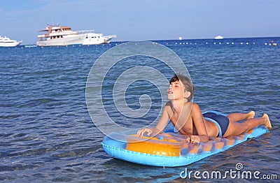Handsome boy in swimming suit with inflatable matress on the blu Stock Photo