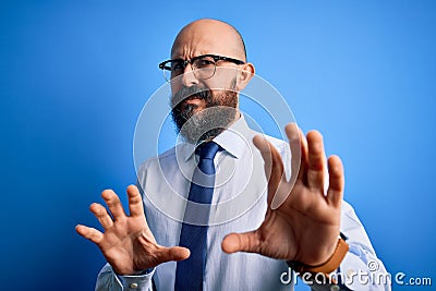 Handsome business bald man with beard wearing elegant tie and glasses over blue background disgusted expression, displeased and Stock Photo