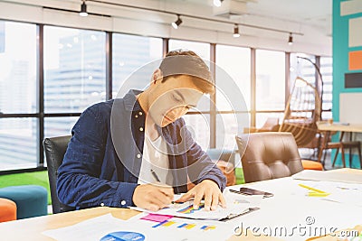 Handsome businessman in eyeglasses is making notes and smiling while working with a laptop at home Stock Photo