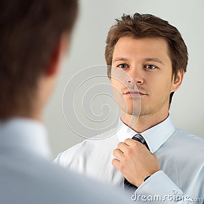 Handsome businessman preparing to official event, straighten tie Stock Photo