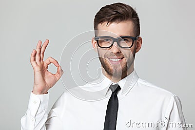 Handsome businessman showing okay sign on gray background. Stock Photo