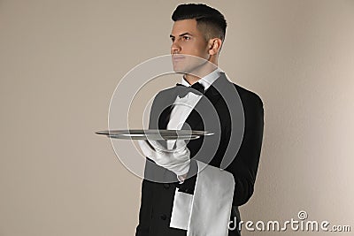 Handsome butler with tray on beige background Stock Photo