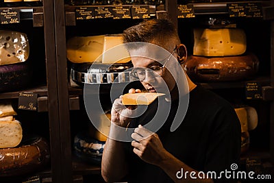 Handsome buyer in cheese shop sniff and enjoy limited gouda cheese. Snack tasty piece of cheese for appetizer. Stock Photo