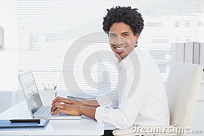 Handsome casual businessman smiling at camera working on laptop Stock Photo