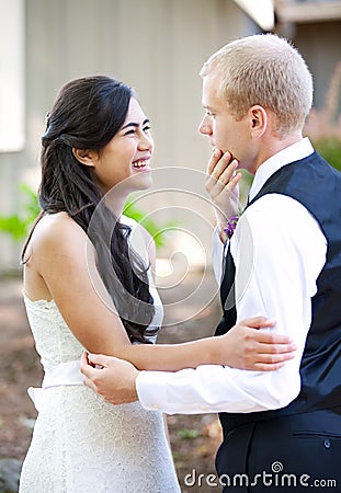 Handsome Caucasian groom talking with his biracial bride outdoor Stock Photo