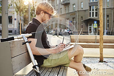 Handsome caucasian man using laptop sitting outdoor in a park. Summer sunshine day. Concept of young business people working Stock Photo