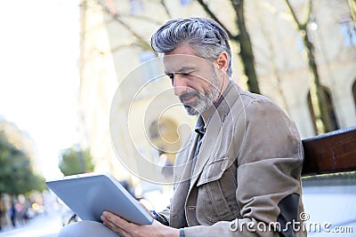 Handsome charming man websurfing on tablet in the streets Stock Photo