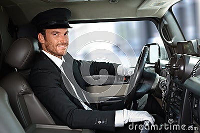 Handsome chauffeur driving limousine smiling Stock Photo