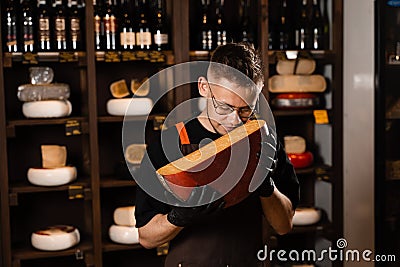 Handsome cheese sommelier holding and sniff limited gouda cheese. Snack tasty piece of cheese for appetizer. Stock Photo