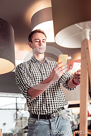 Handsome concentrated customer taking picture of price-tag in lighting store Stock Photo