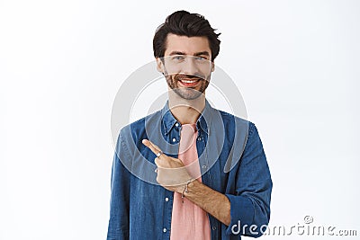 Handsome confident bearded man in stylish outfit, pointing upper left corner, smiling joyfully, give advice where find Stock Photo