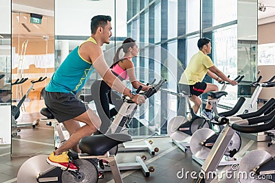 Handsome and confident young man during group class of HIIT indoor cycling Stock Photo