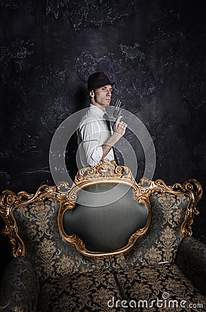 Handsome detective in hat holding a gun in the dark Stock Photo