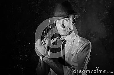 Handsome detective in hat holding a gun in the dark Stock Photo