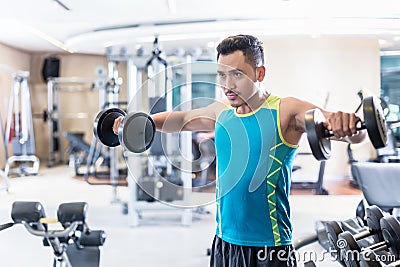 Handsome determined young man exercising with dumbbells in a modern fitness club Stock Photo