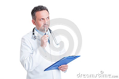 Handsome doctor or medic holding clipboard and thinking Stock Photo