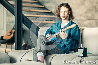 Handsome extraordinary man wearing stylish outfit while training his guitar skills Stock Photo