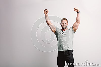 Handsome fit man raising his arms in winning gesture Stock Photo