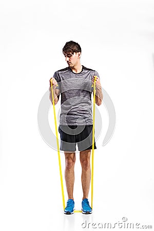 Handsome fitness man working out with rubber band, studio shot. Stock Photo