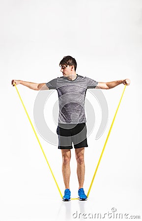 Handsome fitness man working out with rubber band, studio shot. Stock Photo