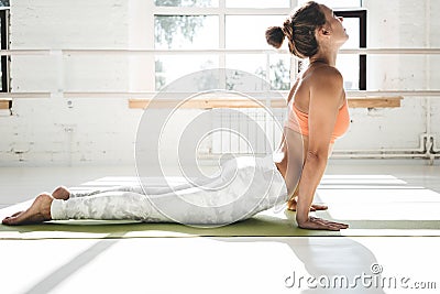 Handsome girl practice cobra asana in sunny gym Stock Photo