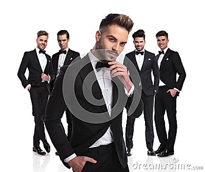 Handsome groom with beard stands in front of group thinking Stock Photo