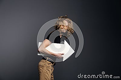 handsome guy in a black T-shirt with long blonde hair runs briskly holding an arrow in his hands on a gray background Stock Photo